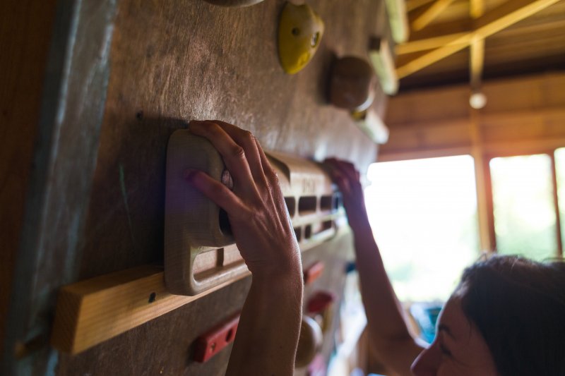 Person hanging onto a rock wall in a home gym (Photo by zhukovvvlad - stock.adobe.com)